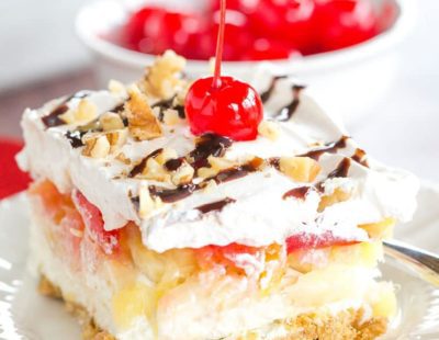 No Bake Banana Split Dessert is a classic! It layers a graham cracker crust, cream cheese-based filling, bananas, pineapple, strawberries, whipped cream, nuts, chocolate & a cherry on top!