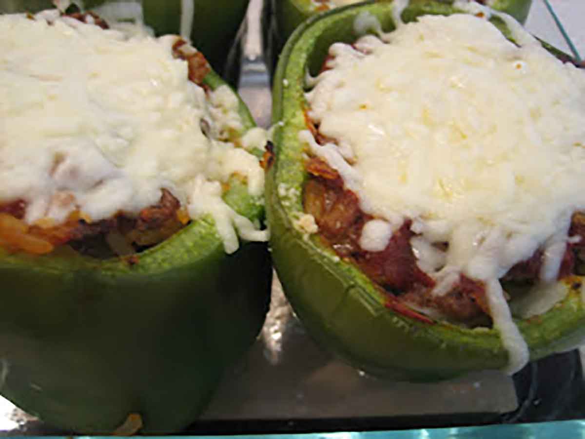 Two green bell peppers stuffed with a meat and rice mixture and topped with melted mozzarella cheese.