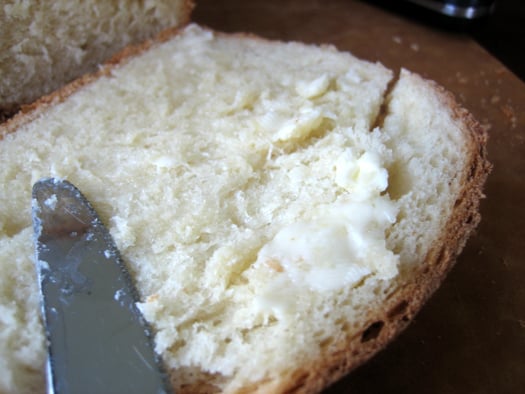 Spreading butter onto a piece of sandwich bread.
