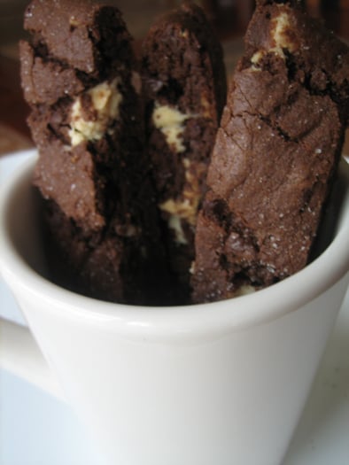 Pieces of chocolate biscotti in a white mug.