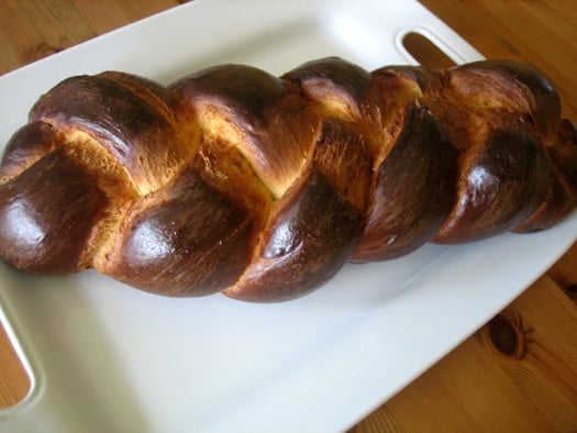 Loaf of challah bread on a white plate.