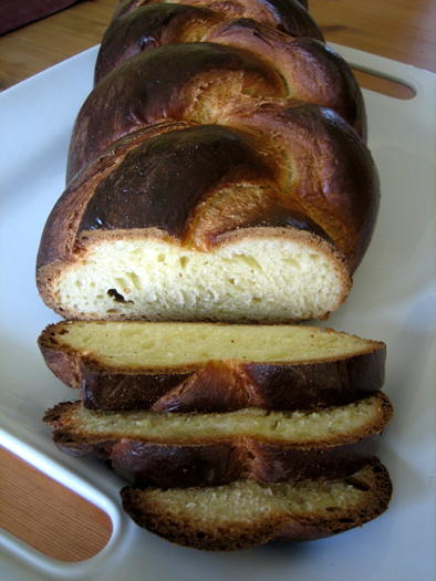 Sliced loaf of challah bread on a white plate.