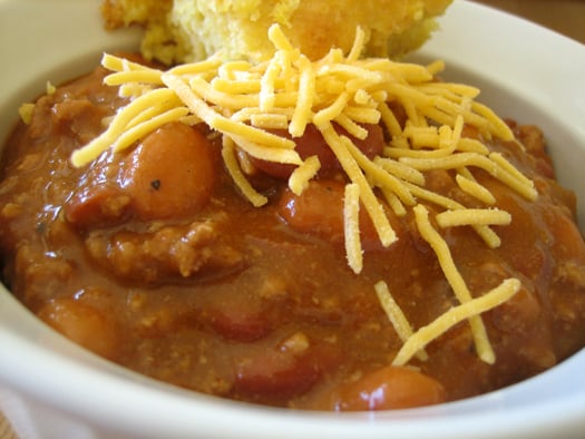 Close up image of chili in a white bowl topped with shredded cheese.