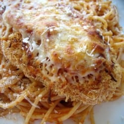 Chicken parmesan on top of noodles on a white plate.