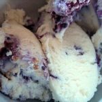 Scoops of blueberry cheesecake ice cream in a white bowl.