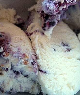 Scoops of blueberry cheesecake ice cream in a white bowl.