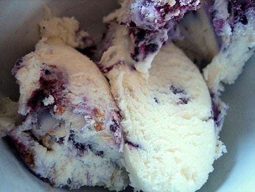 Scoops of blueberry cheesecake ice cream in a white bowl.