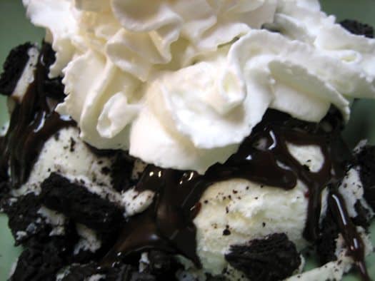 Vanilla ice cream topped with whipped cream, chocolate sauce, and crushed chocolate cookies.