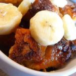 Bread pudding with banana slices in a white mug.