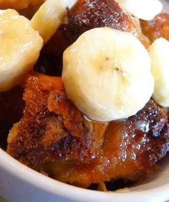 Bread pudding with banana slices in a white mug.
