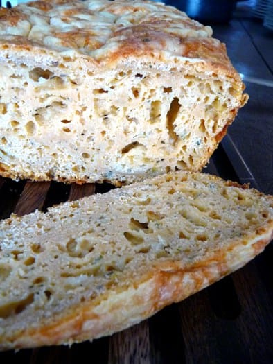 Three cheese beer bread with a slice removed showing the inside texture.