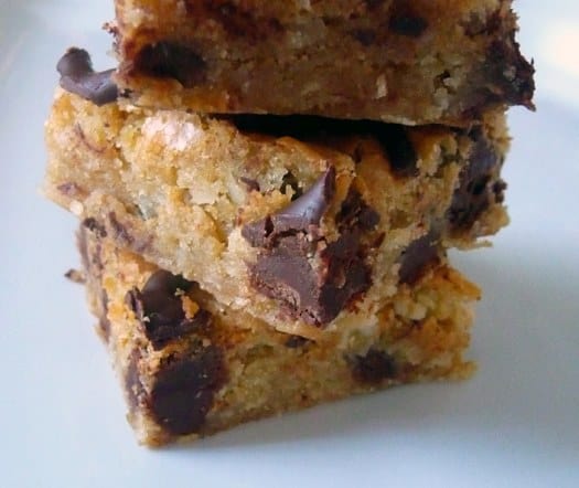 Stack of coconut chocolate chunk blondies on a white plate.