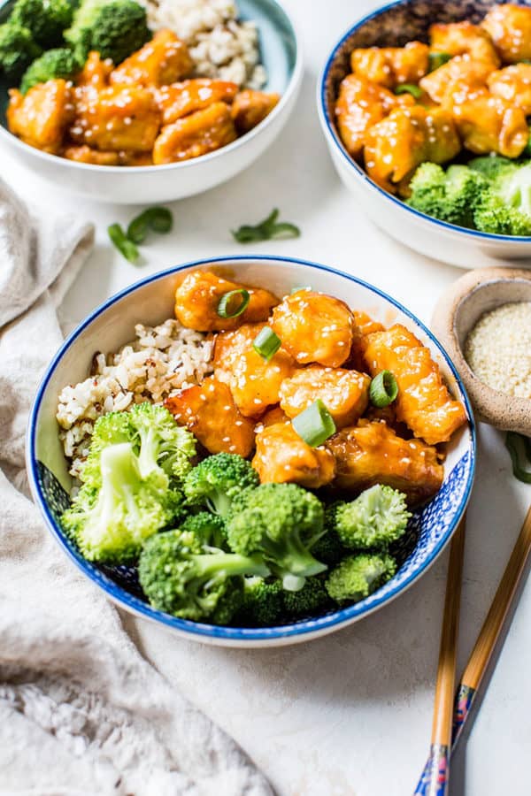 Three bowls of sweet and sour chicken with rice and broccoli.