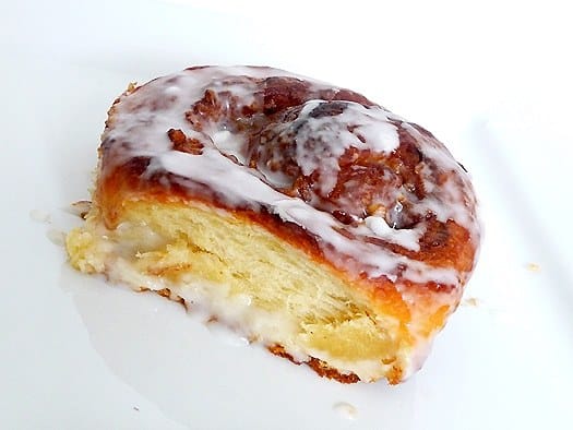 Cream cheese cinnamon roll on a white plate.