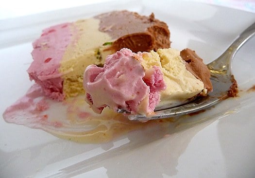 Slice of spumoni ice cream terrine on a white plate with a fork.