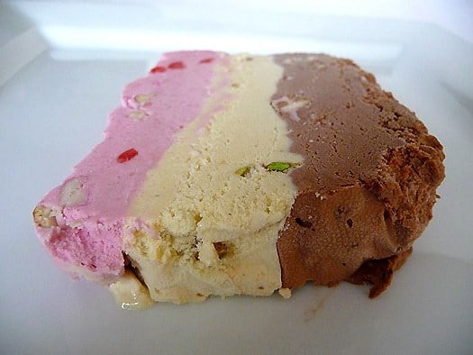 Slice of spumoni ice cream terrine on a white plate.