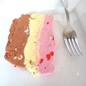 Slice of spumoni ice cream terrine on a white plate with a fork.