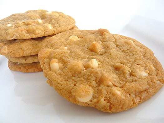 5 white chocolate macadamia nut cookies on a white plate.