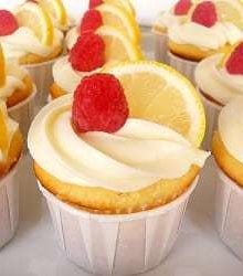 Lemon cupcakes topped with lemon frosting, a lemon slice, and raspberry.