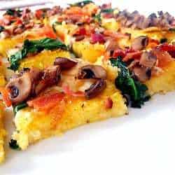 Squares of polenta pizza topped with vegetables.