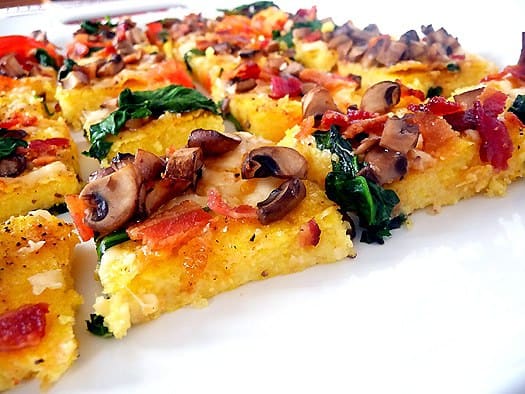 Squares of polenta pizza on a white plate.