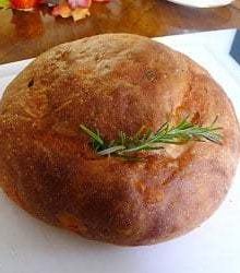 Loaf of potato rosemary bread with a rosemary sprig on top.