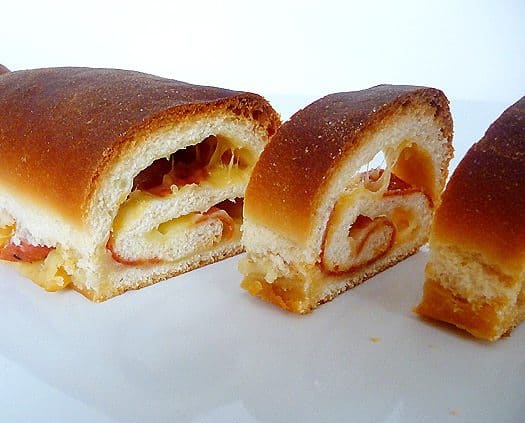 Slices of soft cheese and pepperoni bread on a white plate.