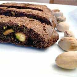 3 slices of chocolate pistachio biscotti on a white plate.