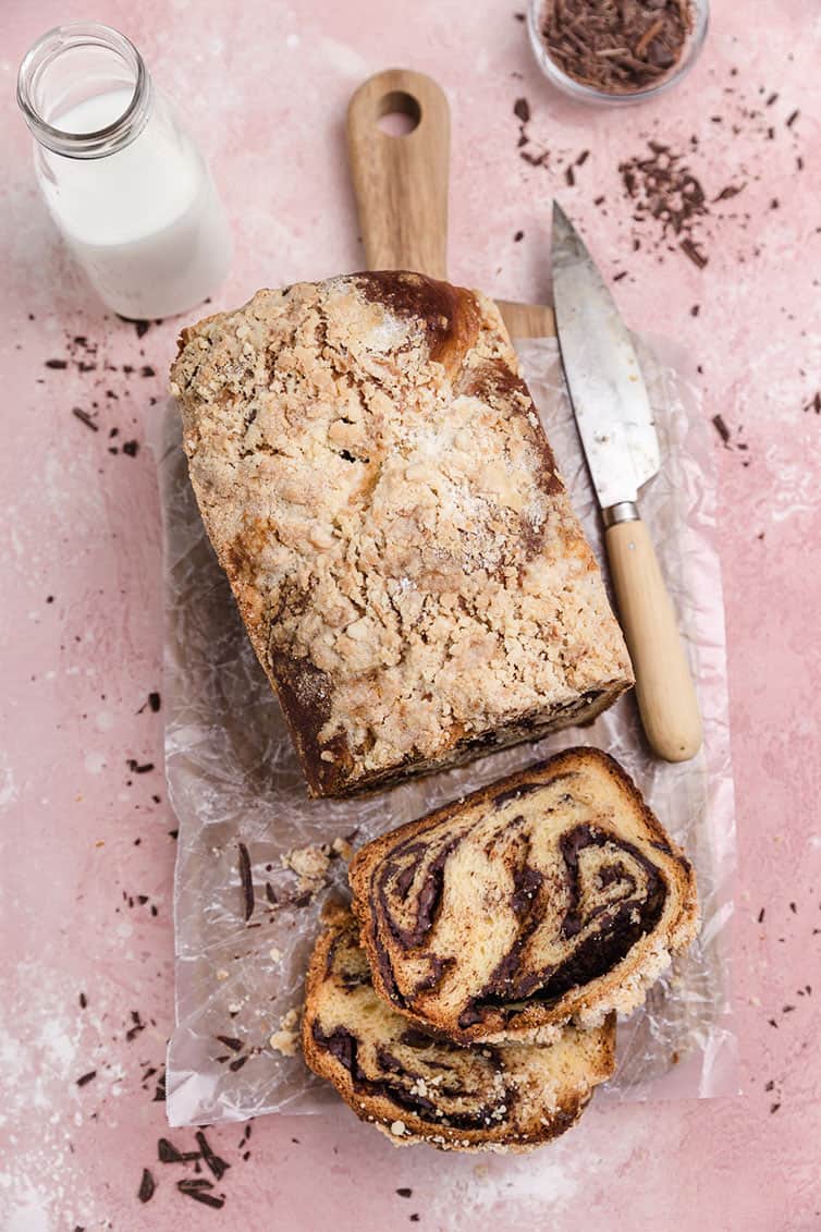 An overhead photo of a loaf of chocolate babka with two slices cut off.