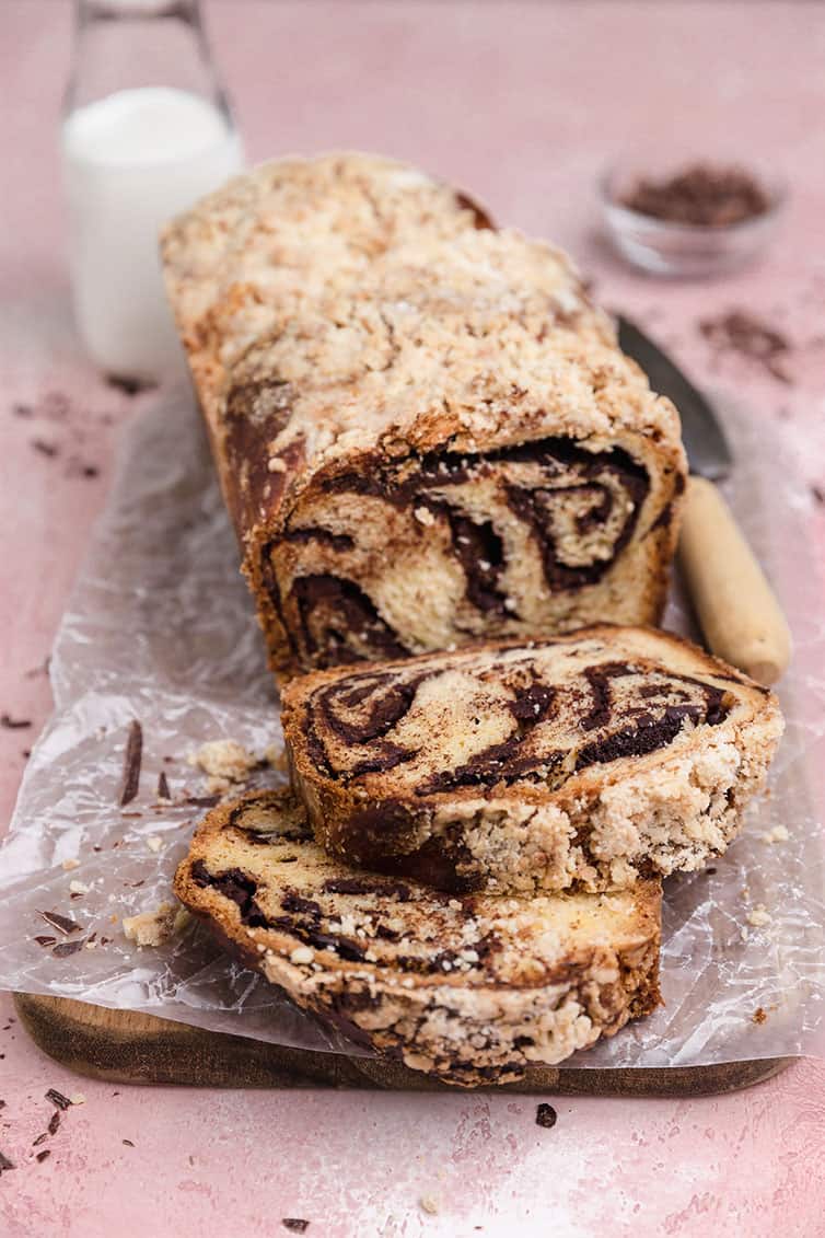 A loaf of chocolate babka with two slices laying in front.
