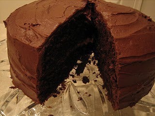 Chocolate layer cake with a slice cut out of it.
