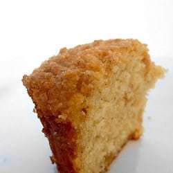 Allspice crumb muffin cut in half on a white plate.