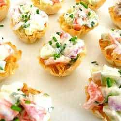 Cucumber tomato bruschetta bites in phyllo dough cups on a serving platter.
