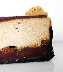 Side view of a slice of peanut butter fudge cheesecake on a white plate.
