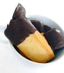 Shortbread cookies with half of each cookie dipped in chocolate in a white mug.