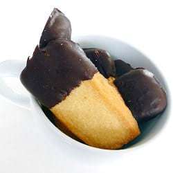 Shortbread cookies with half of each cookie dipped in chocolate in a white mug.