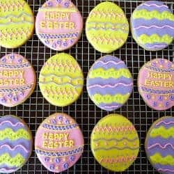 Sugar cookies decorated like Easter eggs on a cooling rack.