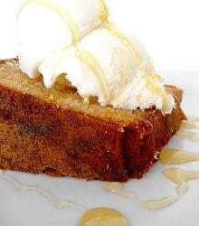 Slice of honey vanilla sour cream pound cake topped with vanilla ice cream and a drizzle of honey.