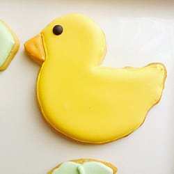 Duck shaped decorated sugar cookie on a white plate.