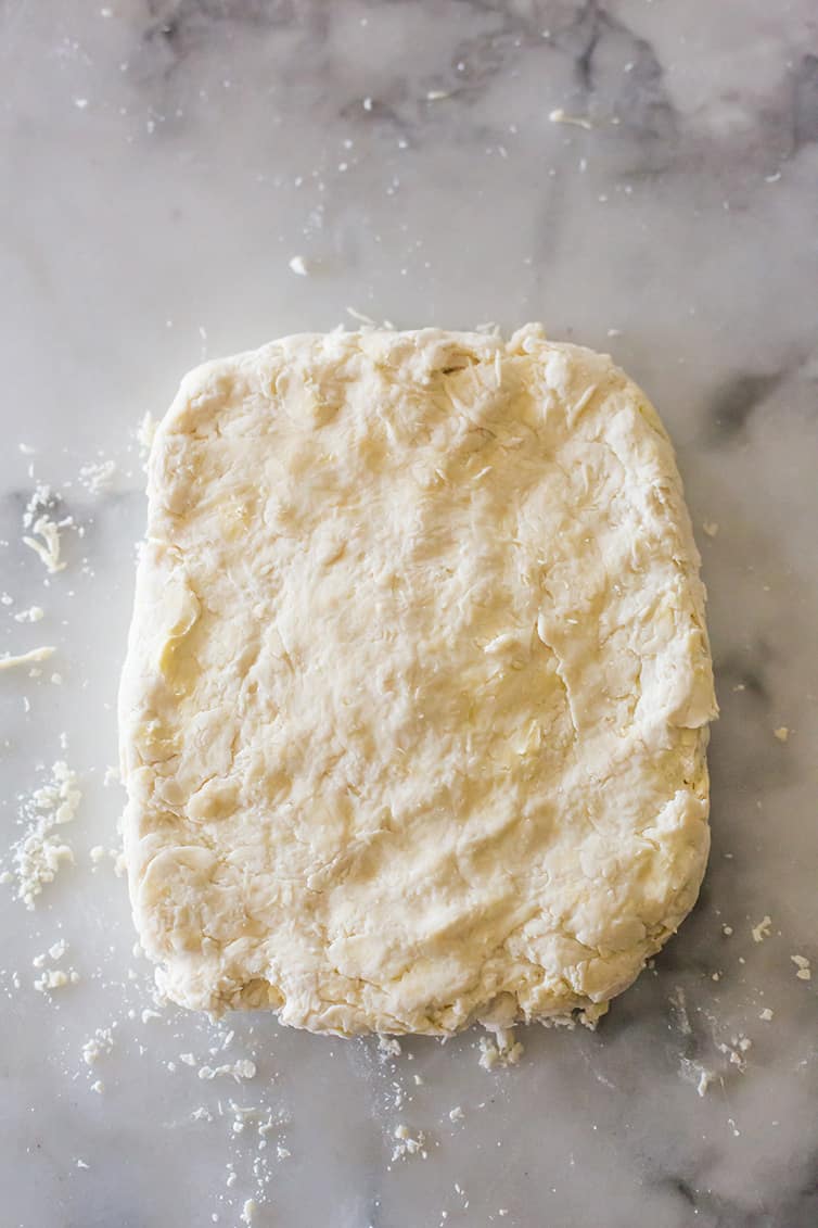 Buttermilk biscuit dough patted into a rectangle.