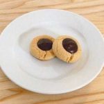 2 chocolate thumbprint cookies on a white plate.