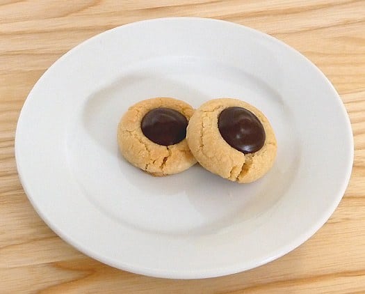 2 chocolate thumbprint cookies on a white plate.