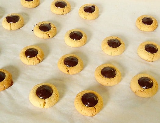Chocolate thumbprint cookies on a baking sheet lined with parchment paper.