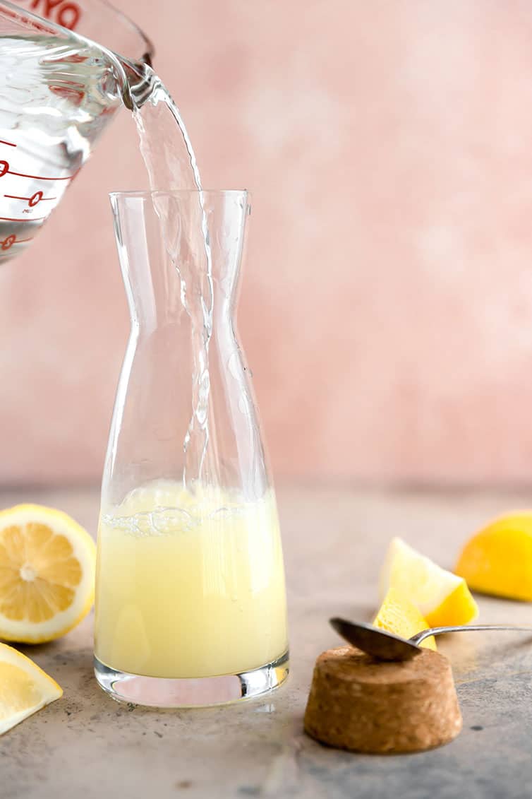 Pouring water into a lemon juice-sugar mixture.