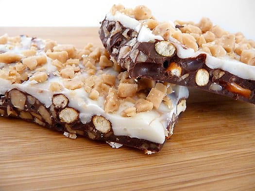 2 pieces of toffee pretzel bark on a wood serving board.