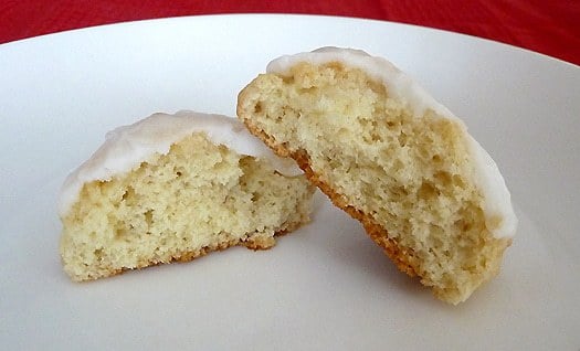 One anise cookie broken in half showing the inside texture on a white plate.