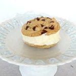Chocolate chip cookie ice cream sandwich with vanilla ice cream on a white dessert stand.