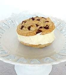 Chocolate chip cookie ice cream sandwich with vanilla ice cream on a white dessert stand.