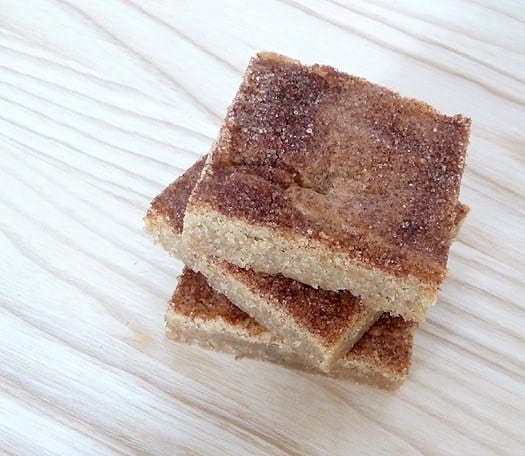 Overhead image of a stack of 3 snickerdoodle blondies on a wood surface.