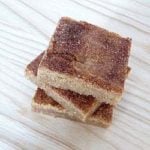 Overhead image of a stack of 3 snickerdoodle blondies on a wood surface.